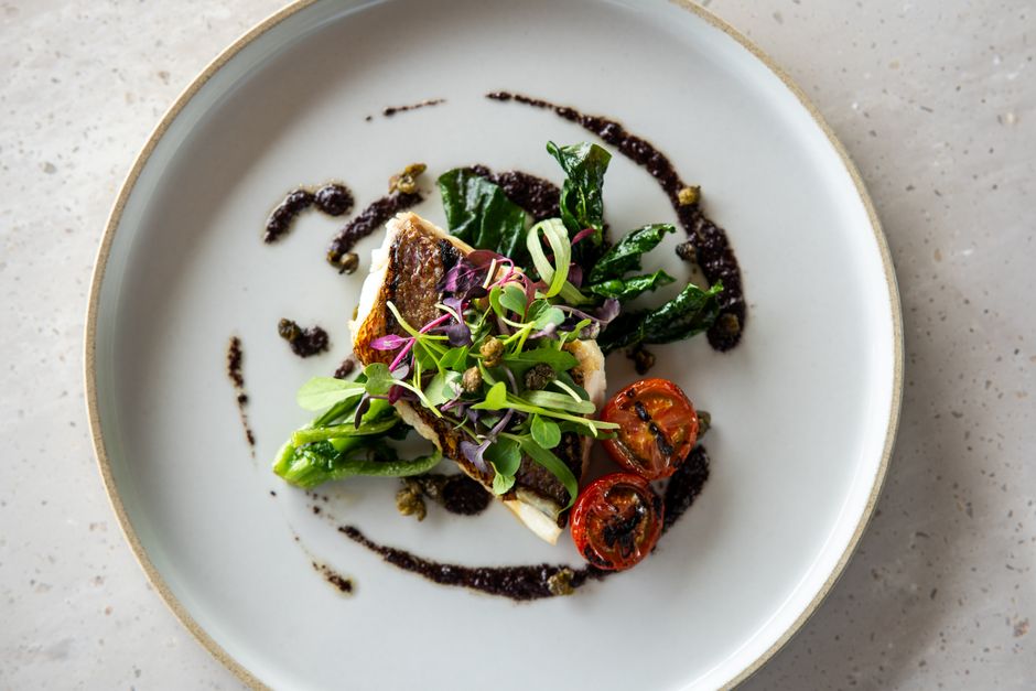 A beautifully plated gourmet dish featuring fresh greens and cherry tomatoes