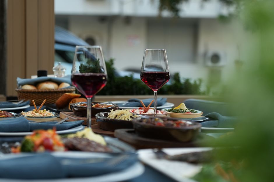 Luxurious outdoor table setting featuring red wine and a variety of gourmet dishes
