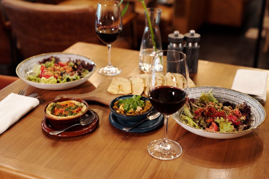 A beautifully arranged table featuring plates of Mediterranean food and glasses of red wine